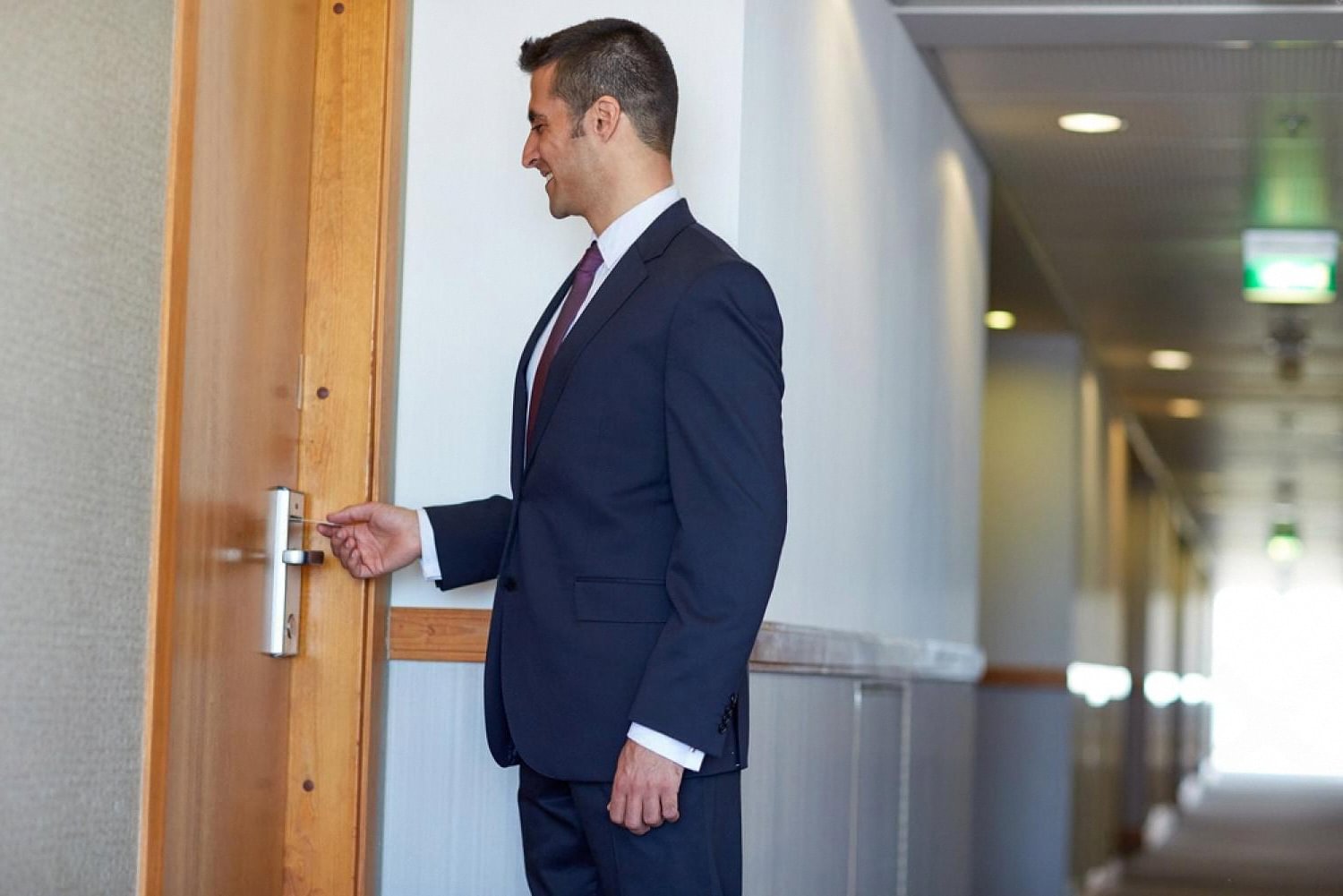 Business traveler tapping a plastic hotel key card on a guest room door